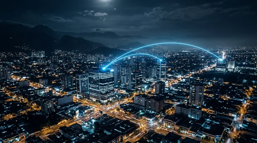 Vista nocturna de una ciudad con enlaces de luz entre dos edificios, que representan la conexión segura entre sedes